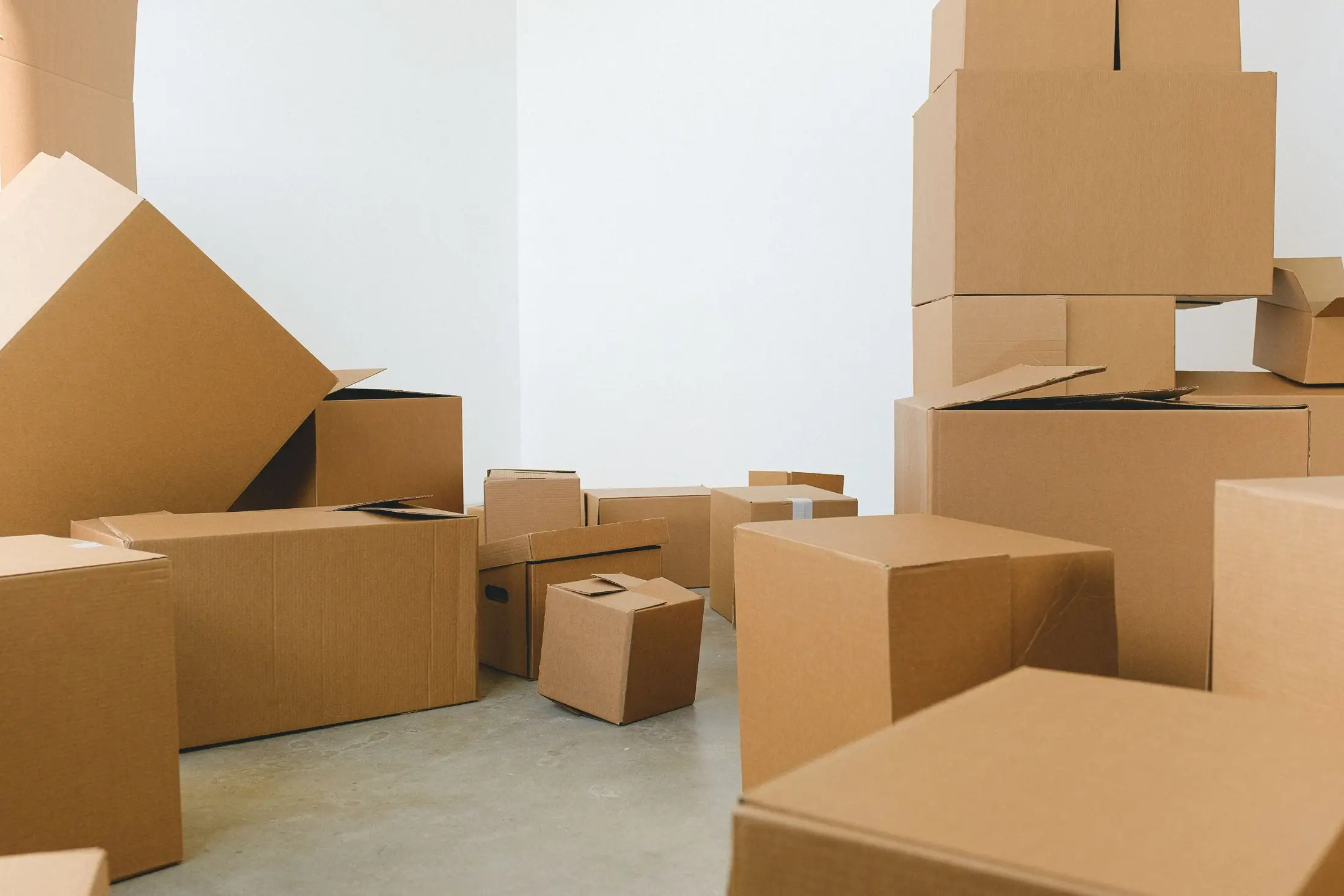 Cartons empilés au milieu d'une pièce vide aux murs blancs